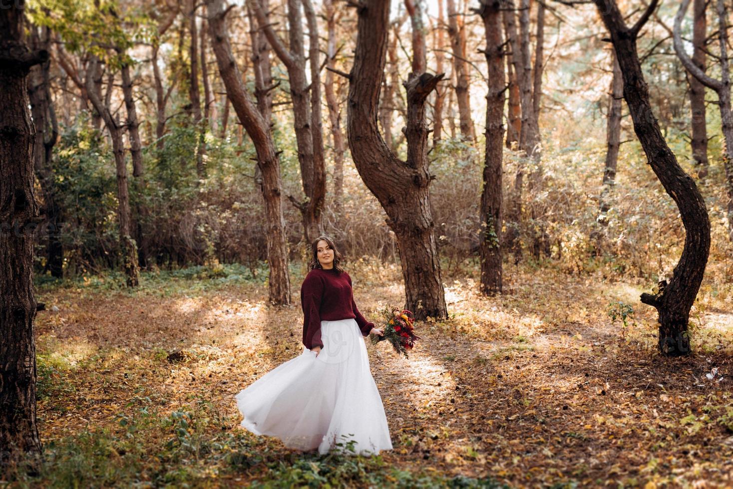 Mädchen im Hochzeitskleid im Herbstwald foto