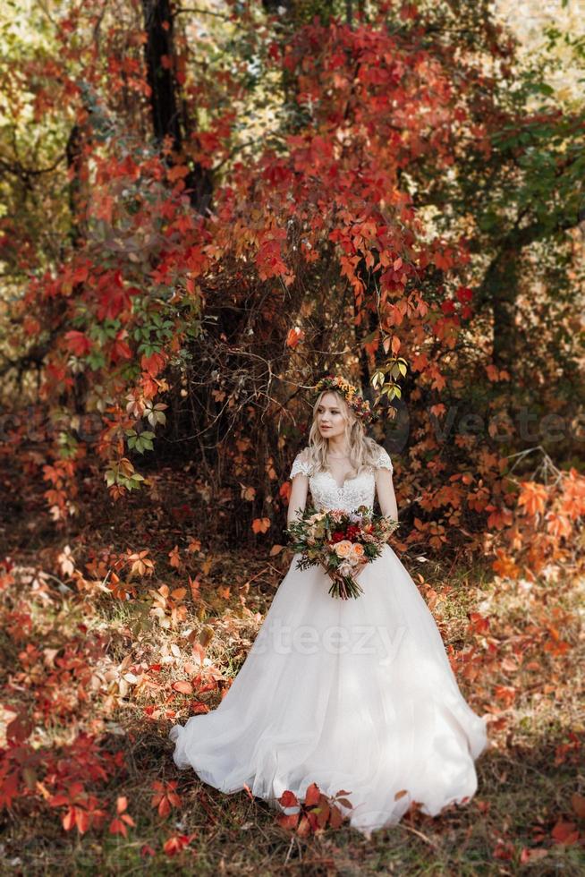 blondes Mädchen in einem Hochzeitskleid im Herbstwald foto