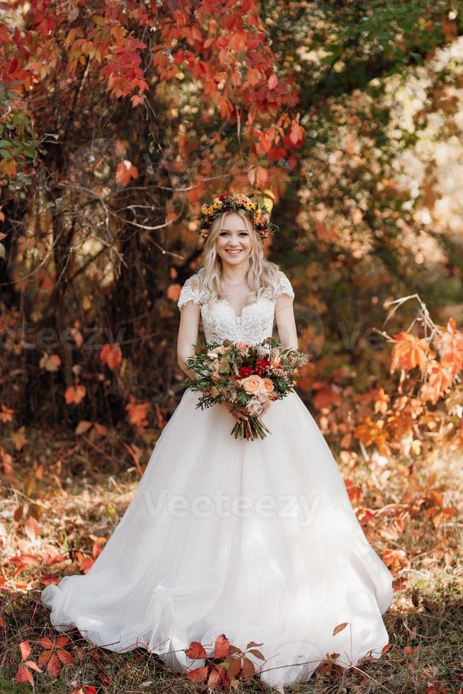 blondes Mädchen in einem Hochzeitskleid im Herbstwald foto