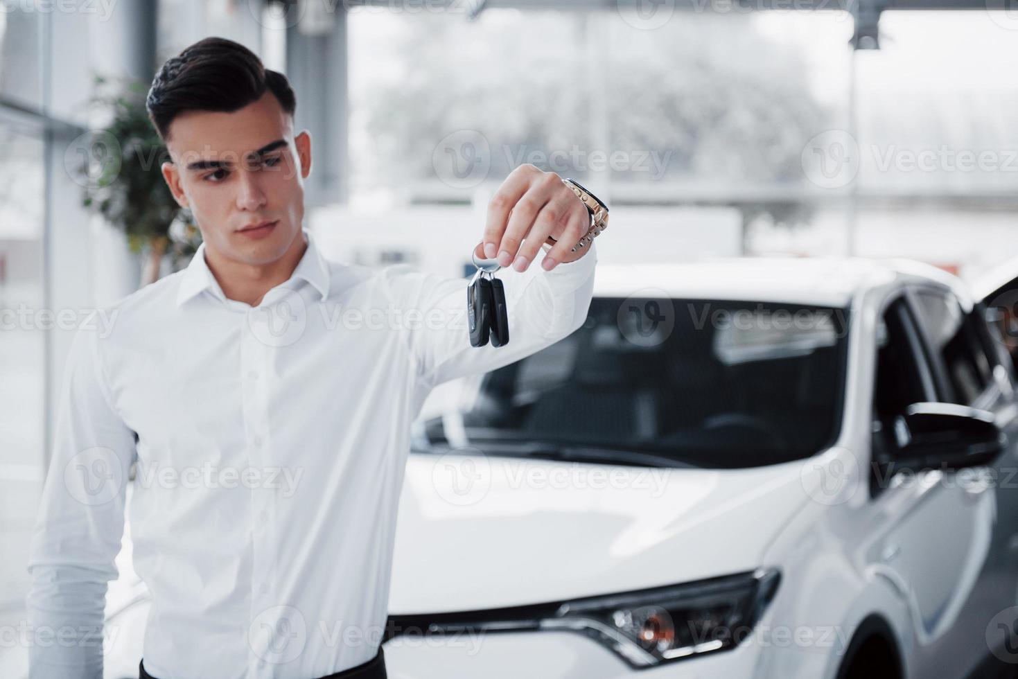 glücklicher junger Mann mit Schlüsseln in den Händen, glücklicher Kauf eines Autos foto