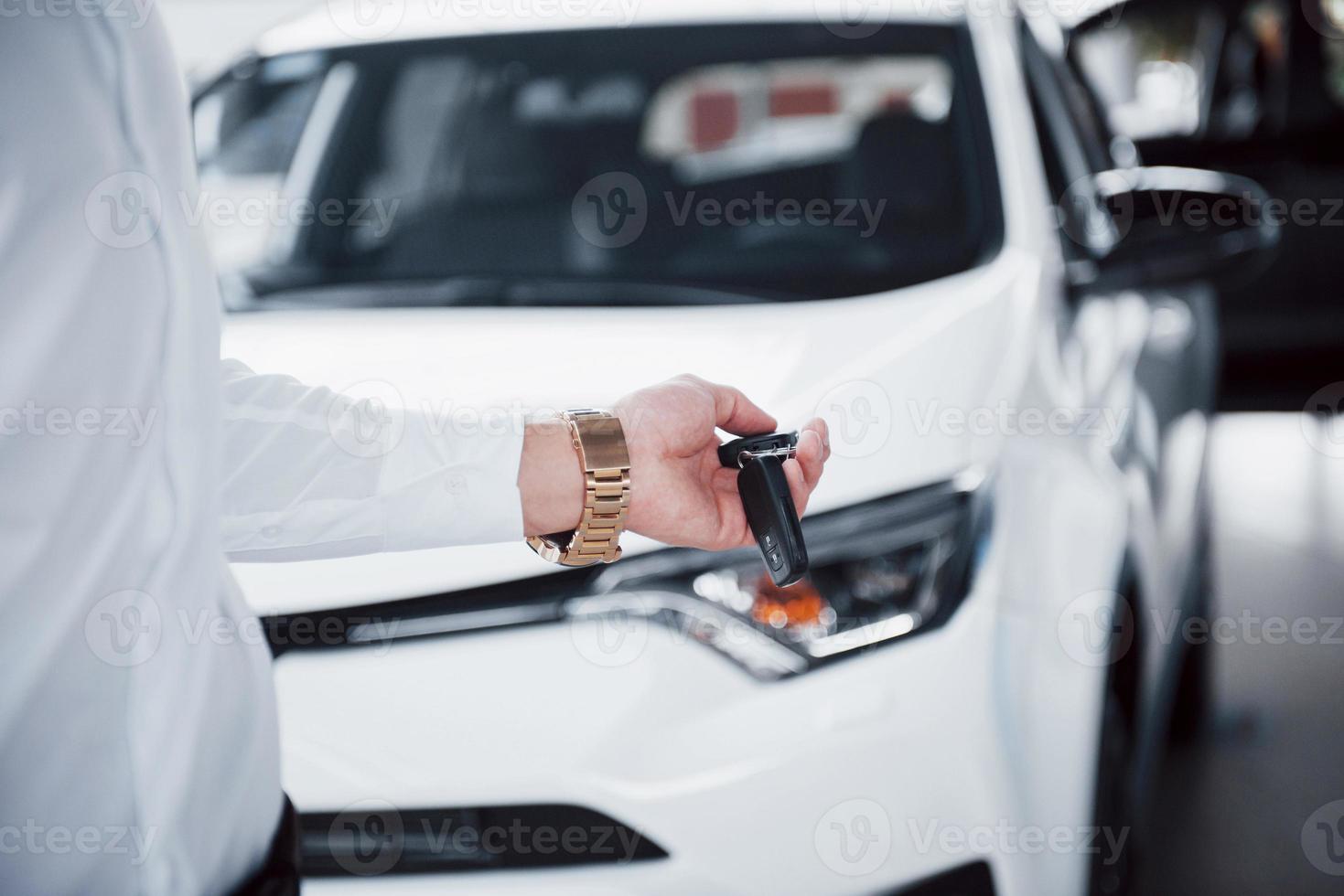 glücklicher junger Mann mit Schlüsseln in den Händen, glücklicher Kauf eines Autos foto