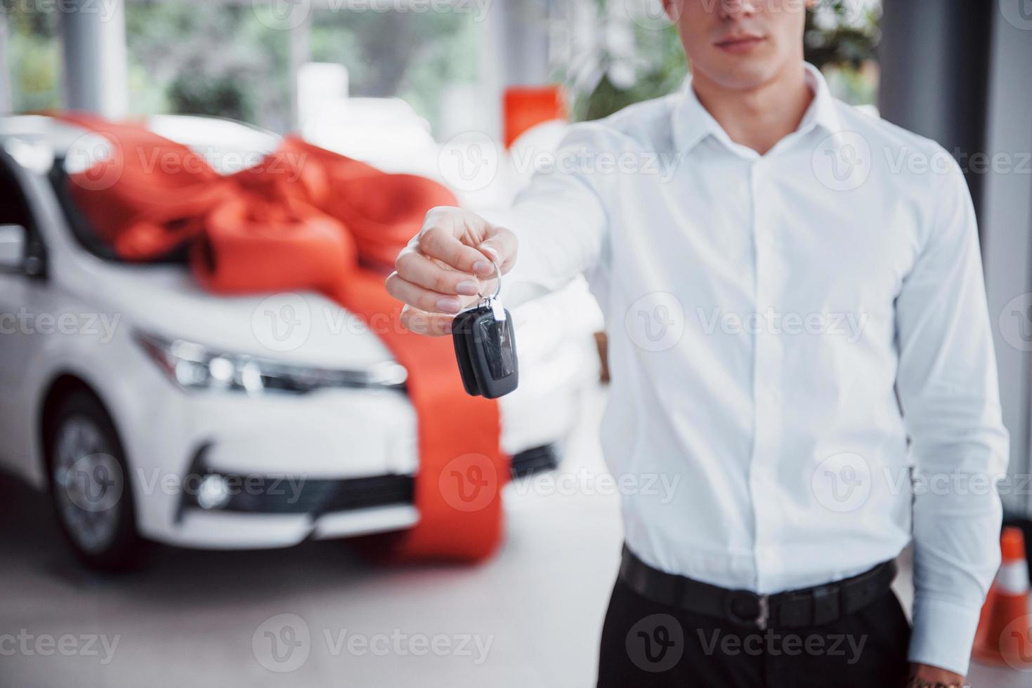 glücklicher junger Mann mit Schlüsseln in den Händen, glücklicher Kauf eines Autos foto