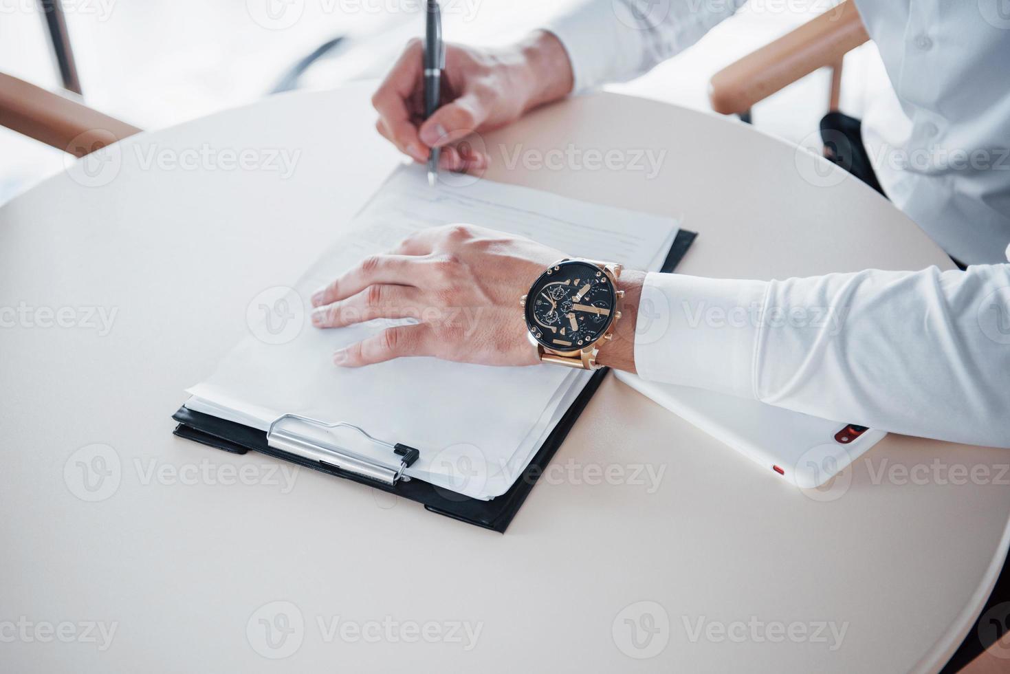 junger Mann unterschreibt Dokumente im Büro, erfolgreicher Verkauf foto