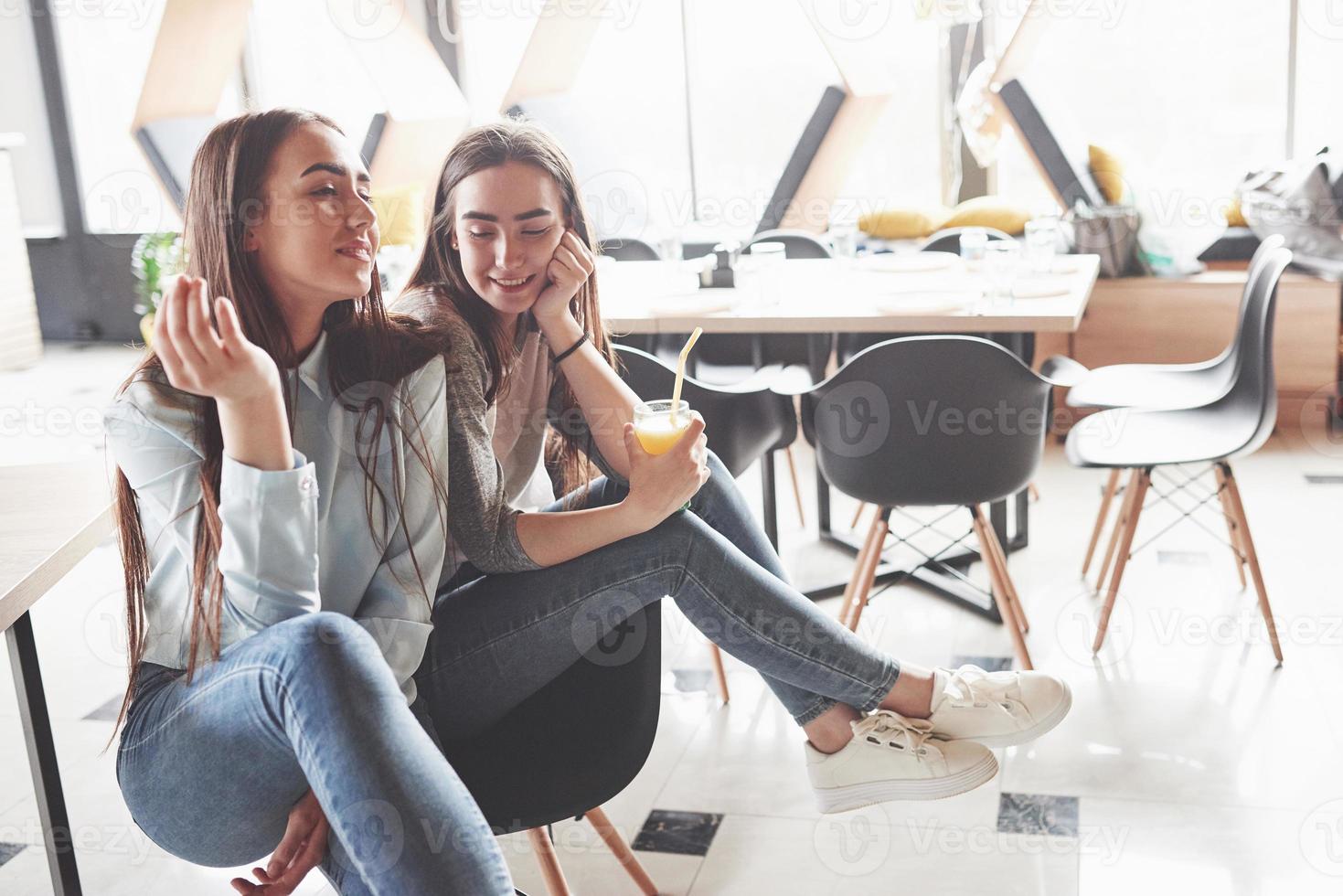 zwei schöne Zwillingsmädchen verbringen Zeit damit, Saft zu trinken. Schwestern, die sich in einem Café entspannen und zusammen Spaß haben foto