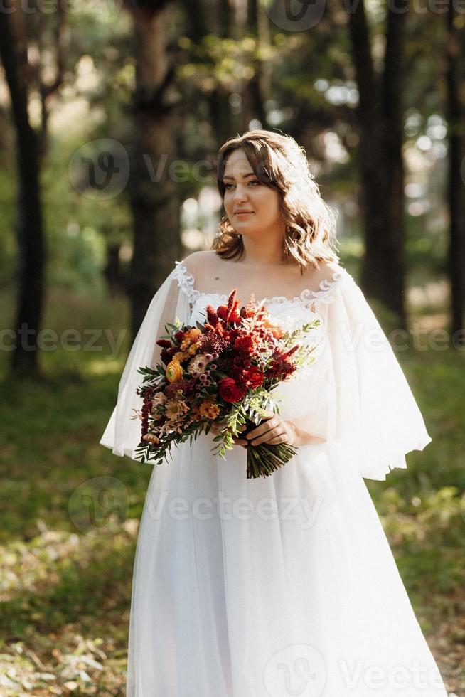 Mädchen im Hochzeitskleid im Herbstwald foto