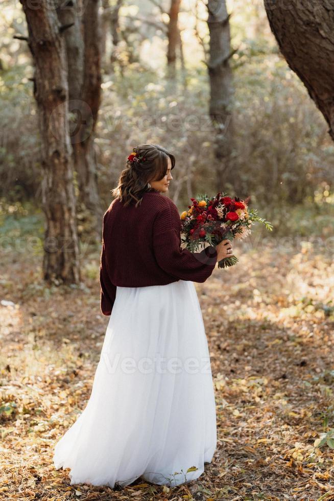 Mädchen im Hochzeitskleid im Herbstwald foto