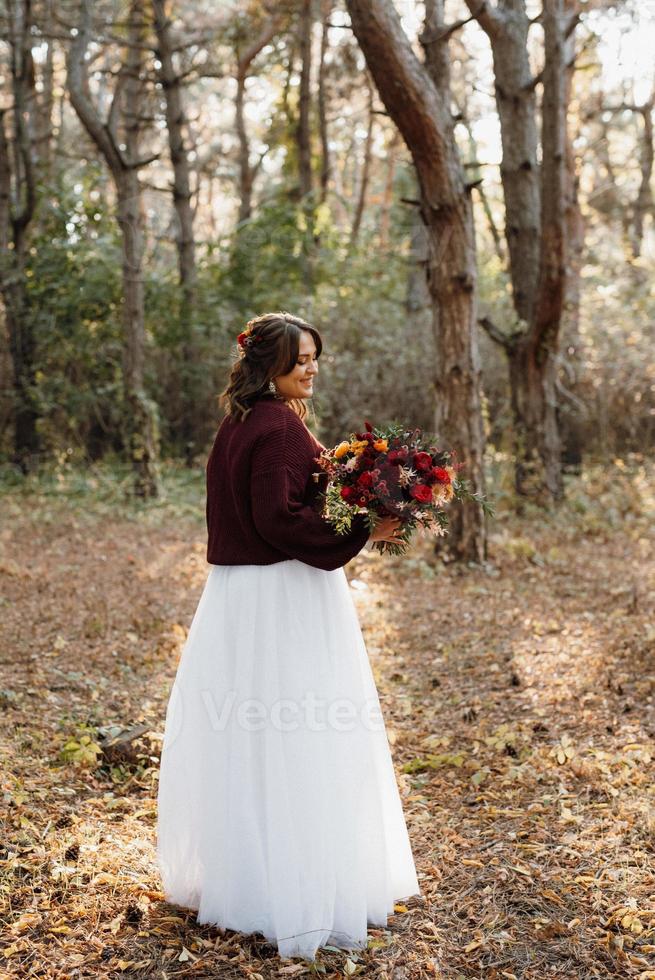 Mädchen im Hochzeitskleid im Herbstwald foto