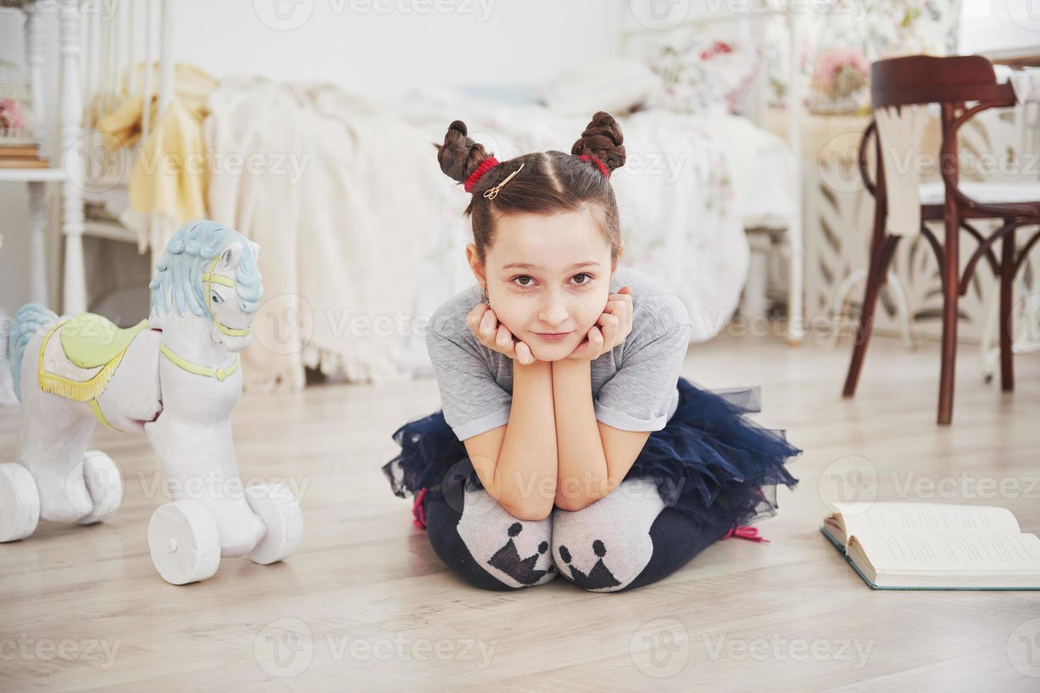 süßes kleines Kindermädchen, das ein Buch im Schlafzimmer liest foto