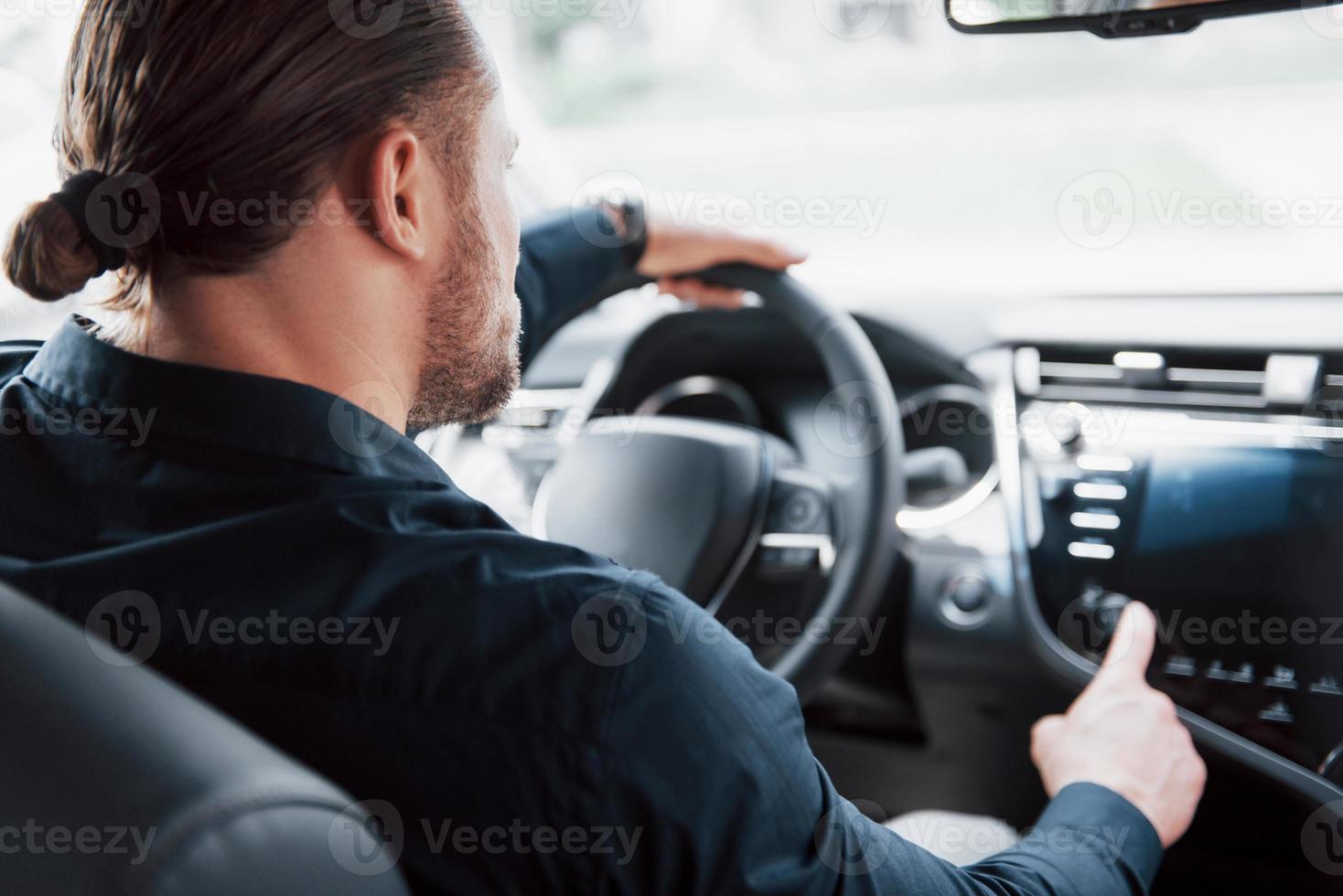 selbstbewusster junger Geschäftsmann, der am Steuer seines neuen Autos sitzt foto