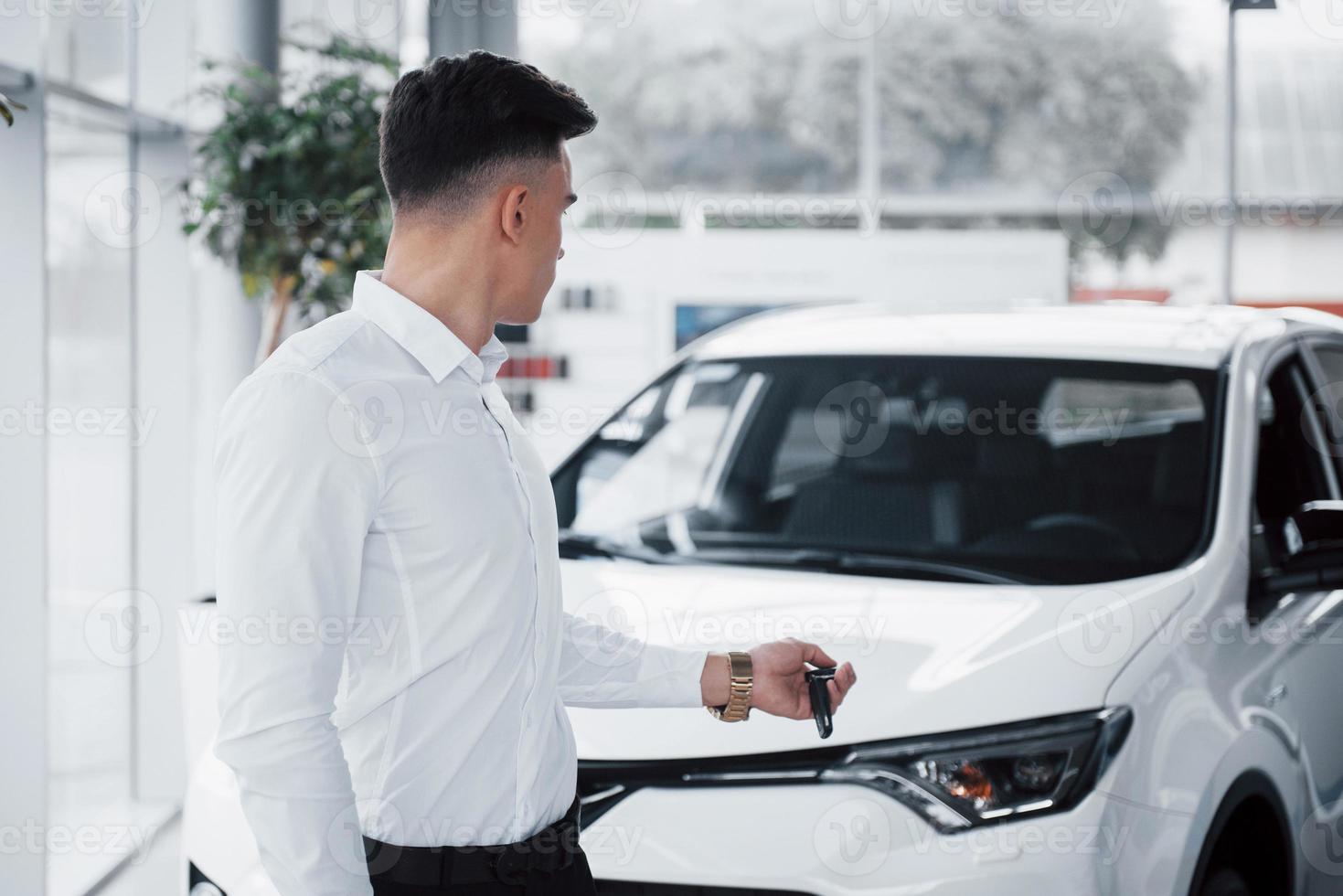 glücklicher junger Mann mit Schlüsseln in den Händen, glücklicher Kauf eines Autos foto