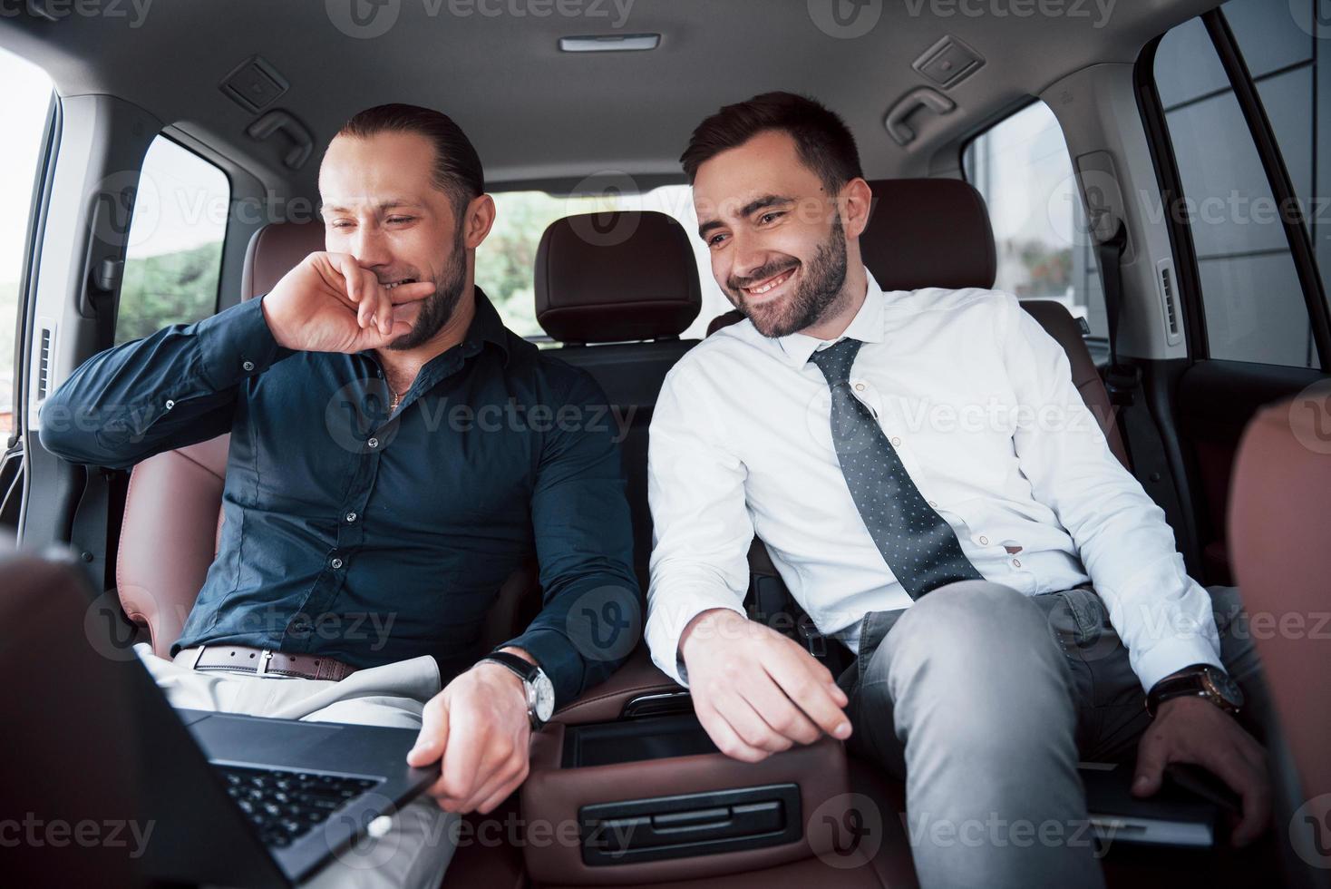 die beiden alten Geschäftsfreunde schließen in ungezwungener Atmosphäre im Innenraum des Autos einen neuen Vertrag ab foto