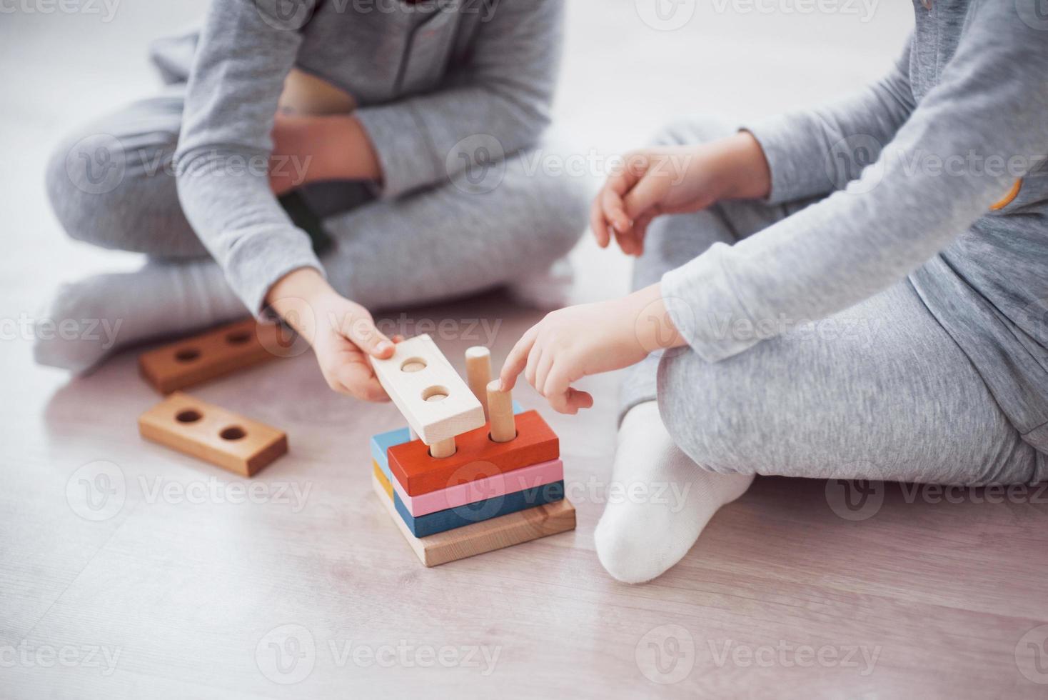 Kinder spielen mit einem Spielzeugdesigner auf dem Boden des Kinderzimmers. zwei Kinder spielen mit bunten Blöcken. Lernspiele im Kindergarten foto