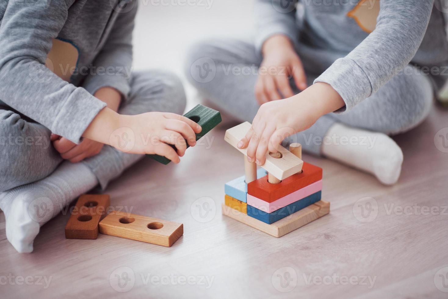 Kinder spielen mit einem Spielzeugdesigner auf dem Boden des Kinderzimmers. zwei Kinder spielen mit bunten Blöcken. Lernspiele im Kindergarten foto