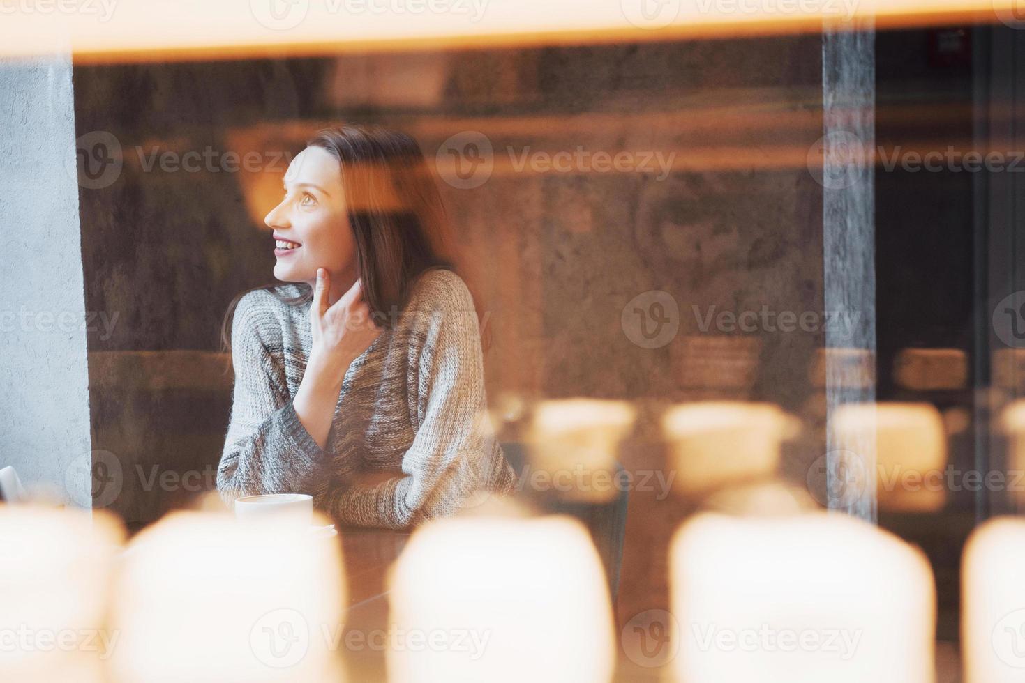 lächelnde Frau im Café mit Handy und SMS in sozialen Netzwerken, allein sitzend foto