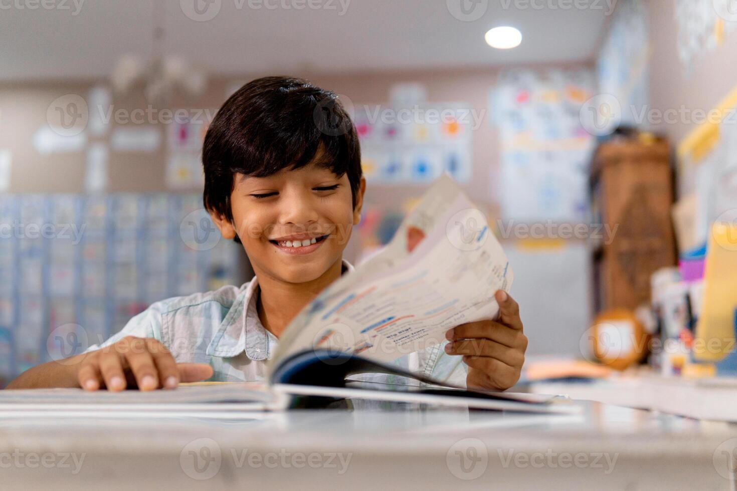 Porträt von elementar Junge lesen ein Buch im ein Klasse. foto