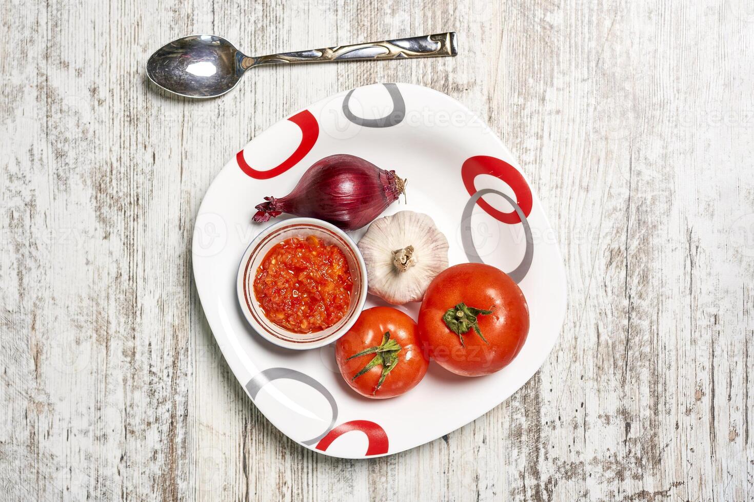 ein Teller mit Tomaten, Zwiebeln, und ein Löffel foto