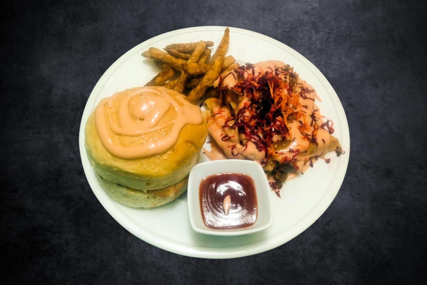 Burger mit Hähnchen hacken, Französisch Fritten, und Soße auf ein Weiß Teller auf ein schwarz Hintergrund foto