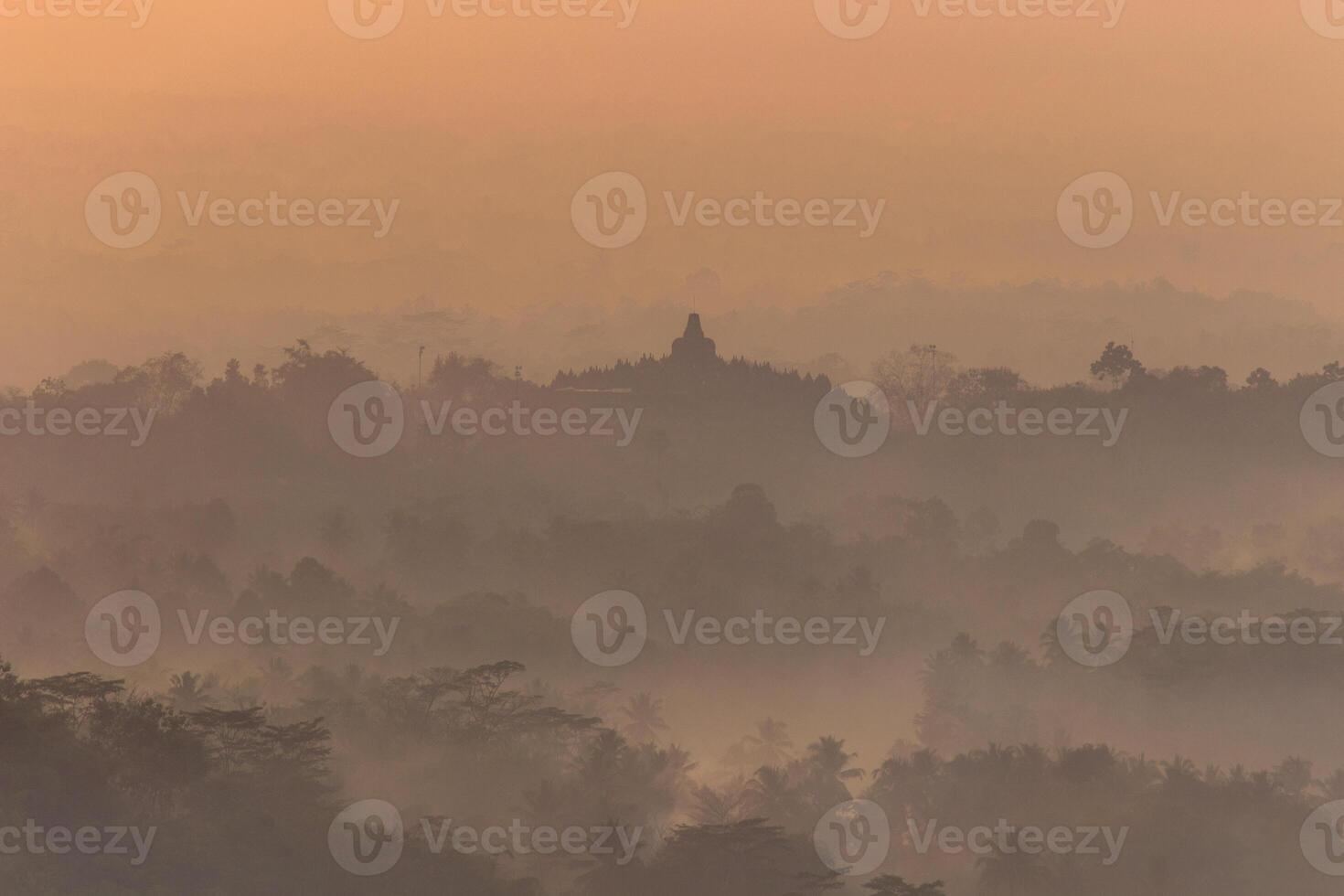 Silhouette von das Borobudur Tempel auf ein neblig Morgen, das golden Farbe von Morgen Licht umgibt das Tempel, Indonesien foto