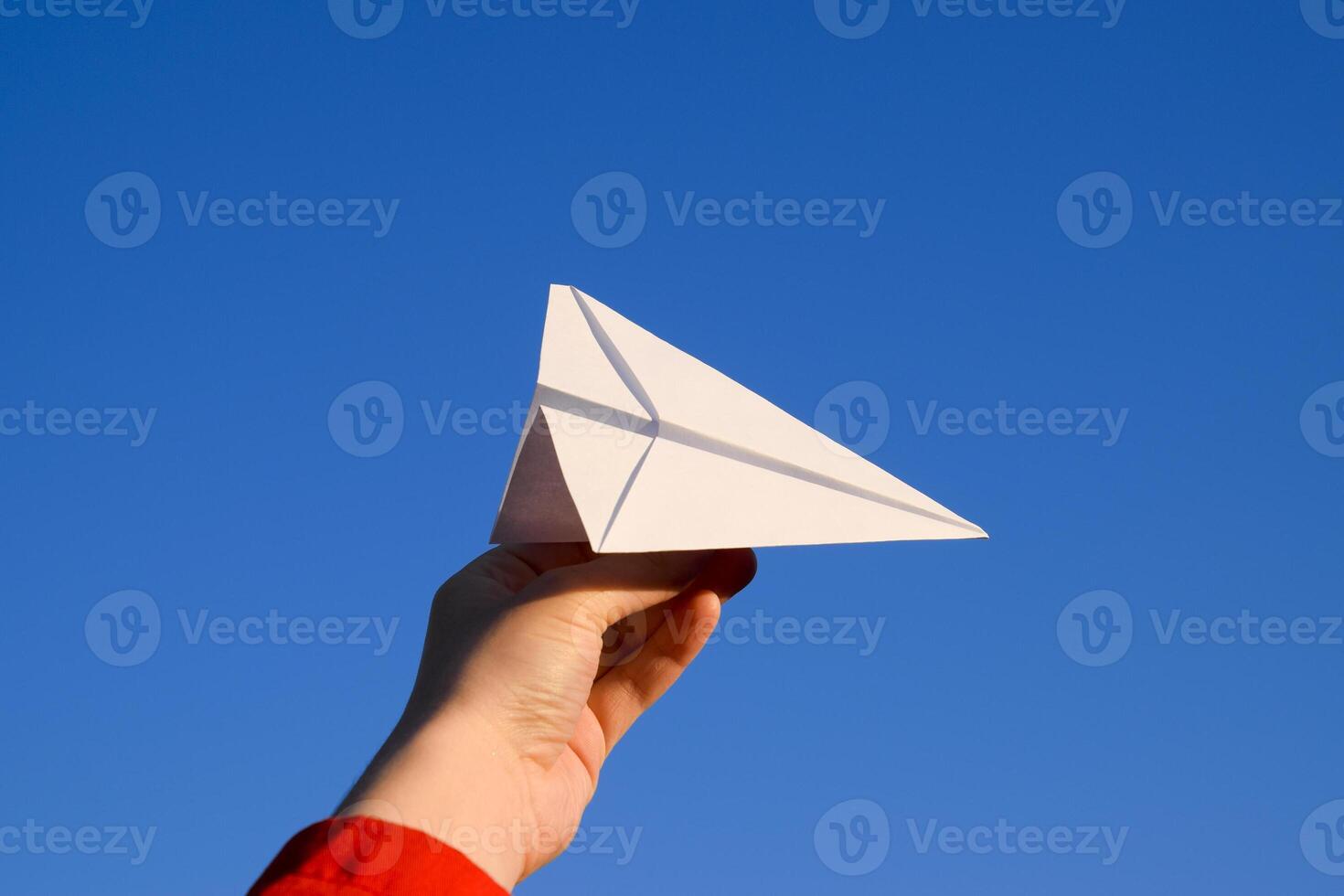 Weiß Papier Flugzeug im Hand gegen das Himmel. ein Symbol von Freiheit auf das Internet foto