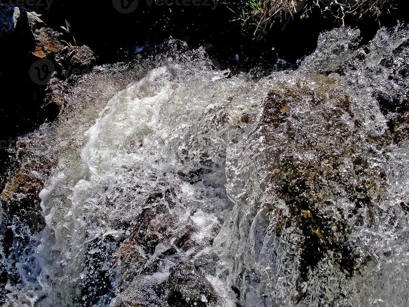 Wasserfall von das aufgetaut Gewässer. schmelzen Schnee im das hügelig tun foto