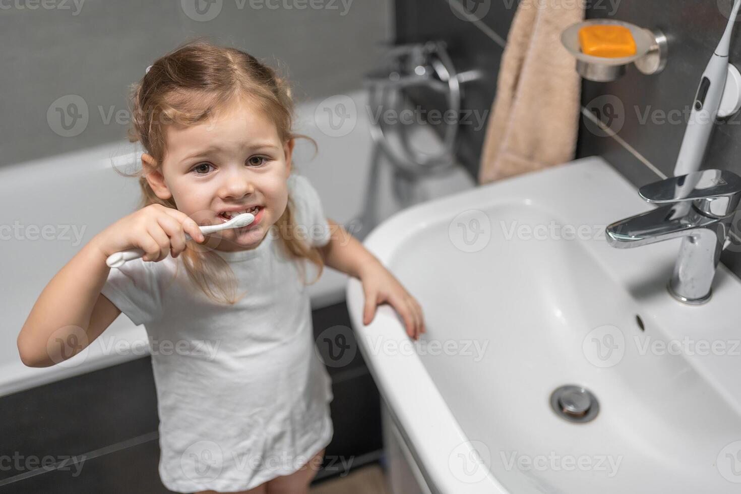 glücklich Kleinkind Mädchen Bürsten Zähne im das Bad foto