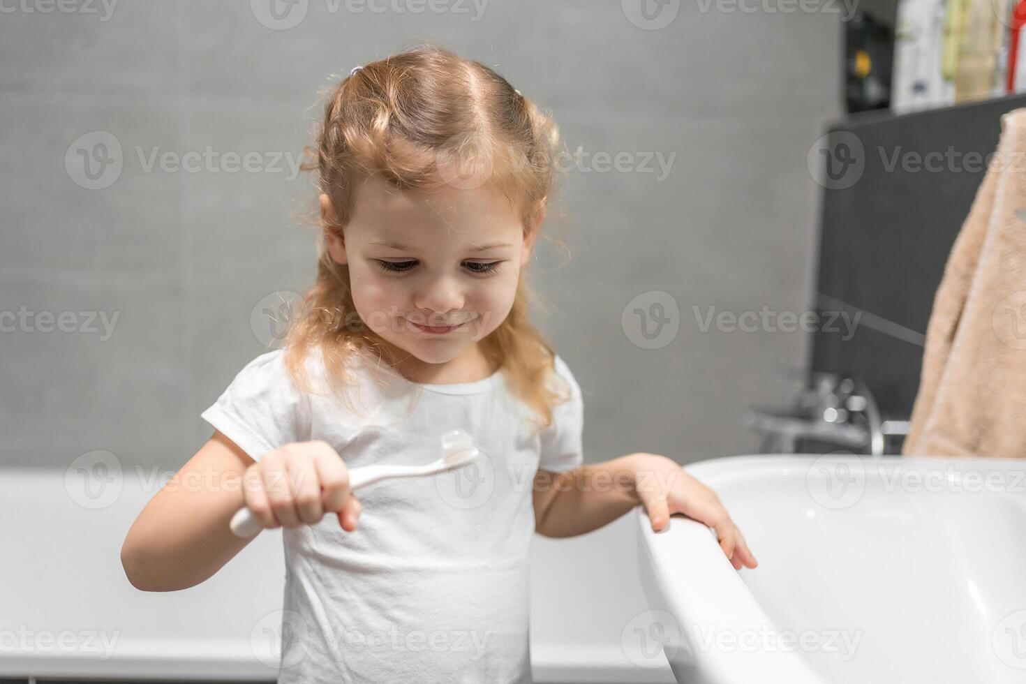 glücklich Kleinkind Mädchen Bürsten Zähne im das Bad foto