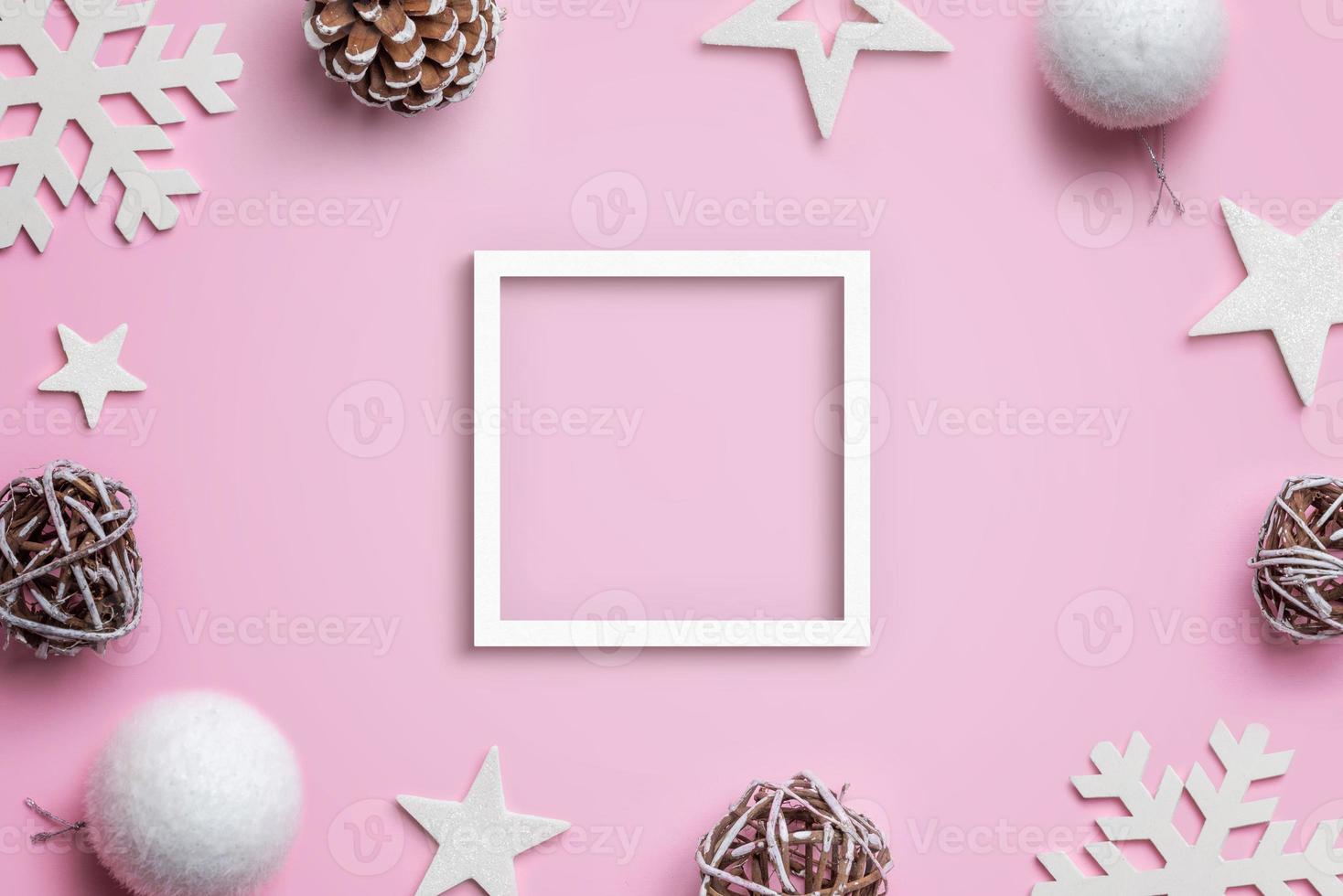weißer Rahmen, umgeben von Weihnachtsschmuck auf rosafarbenem Pastellschreibtisch. Draufsicht, flache Lage, Komposition foto