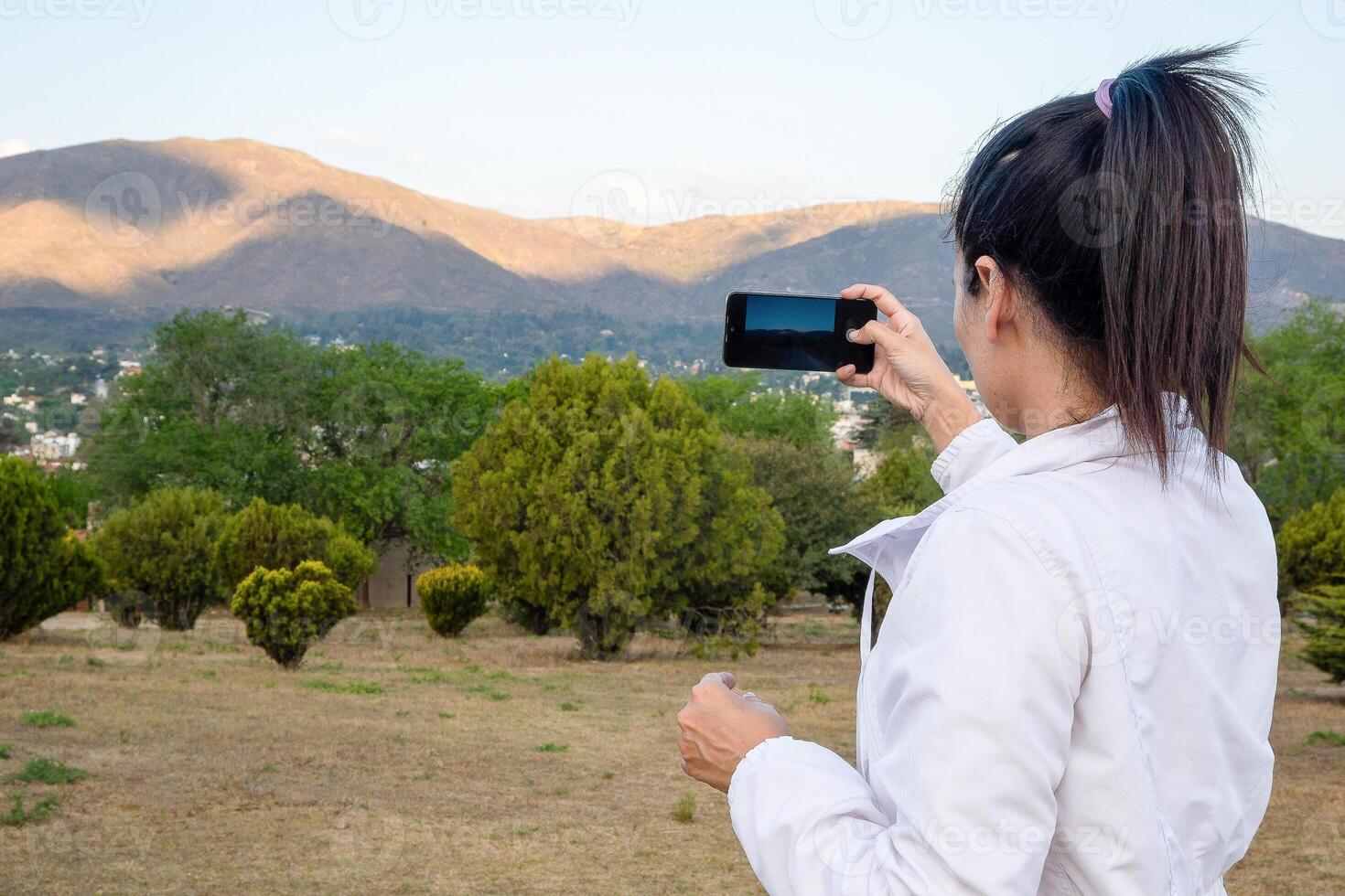 Latein Frau mit ihr Zelle Telefon im ein Park. foto