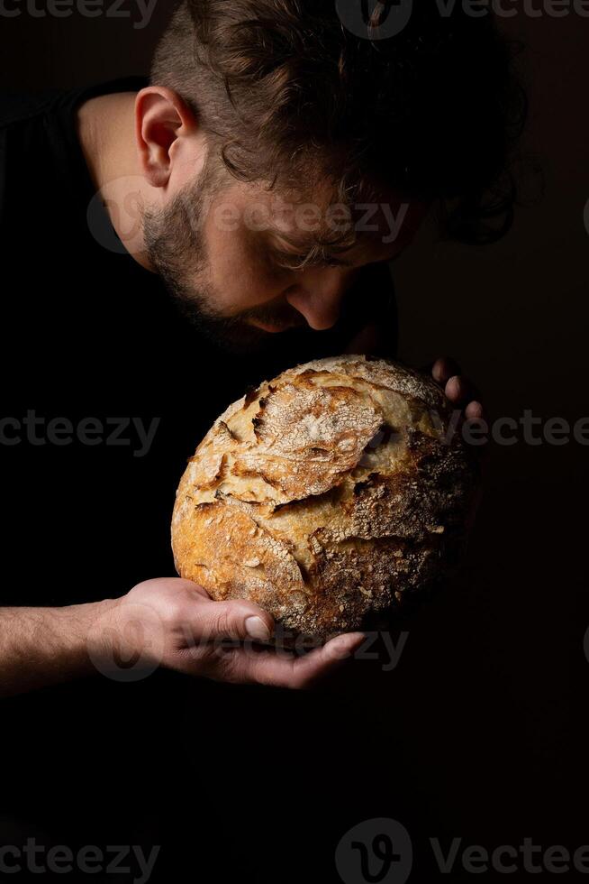 attraktiv jung kaukasisch Koch posieren mit Weiß Sauerteig Brot. foto