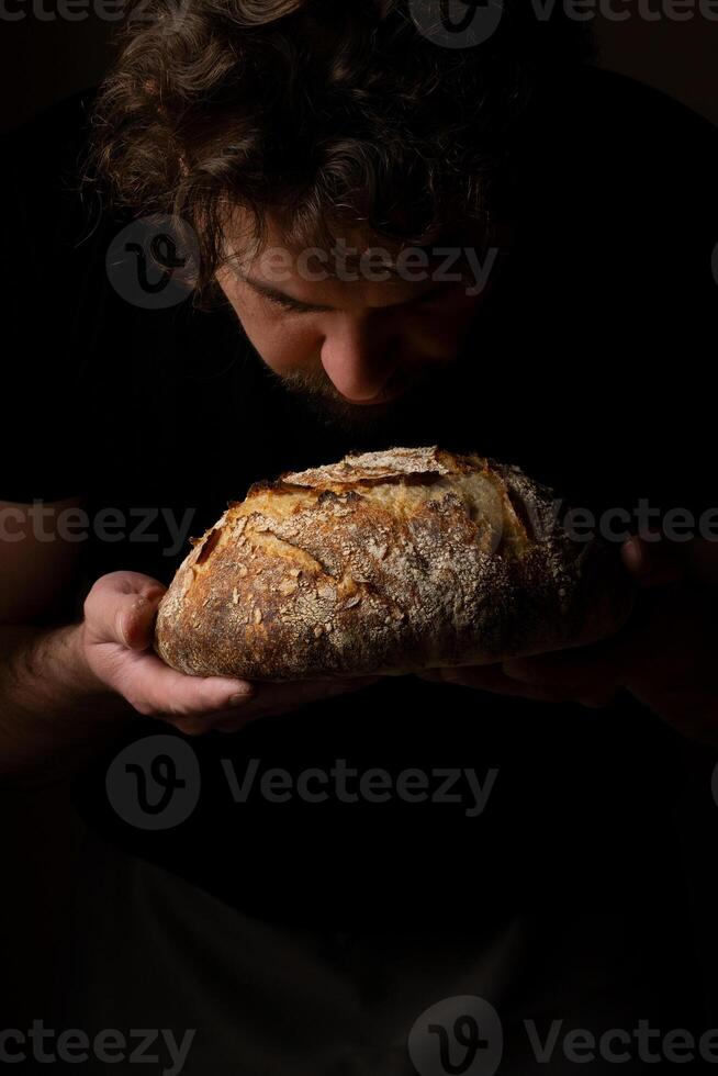 attraktiv jung kaukasisch Koch posieren mit Weiß Sauerteig Brot. foto