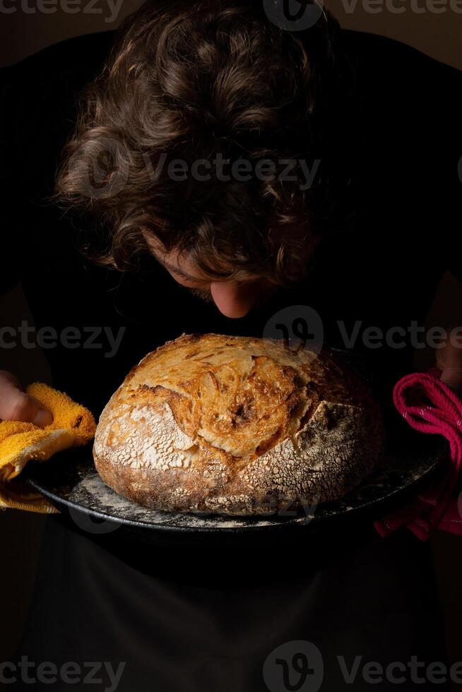 attraktiv jung kaukasisch Koch posieren mit Weiß Sauerteig Brot. foto