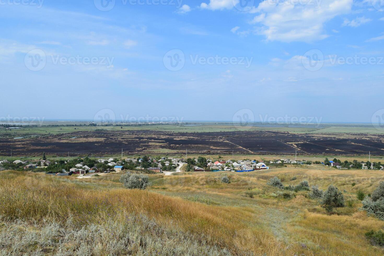 gesprengt Felder draußen das Dorf. das Tatsache Das links ein Feuer auf das Feld. das Dorf von das Hügel Aussicht foto