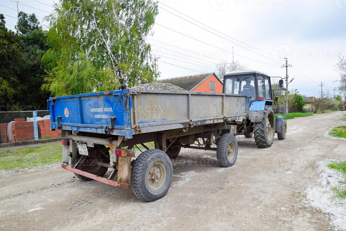 Traktor mit ein Schutt Wagen zum reparieren das Straße. Fütterung Löcher auf das Straße. Straße Reparatur. foto