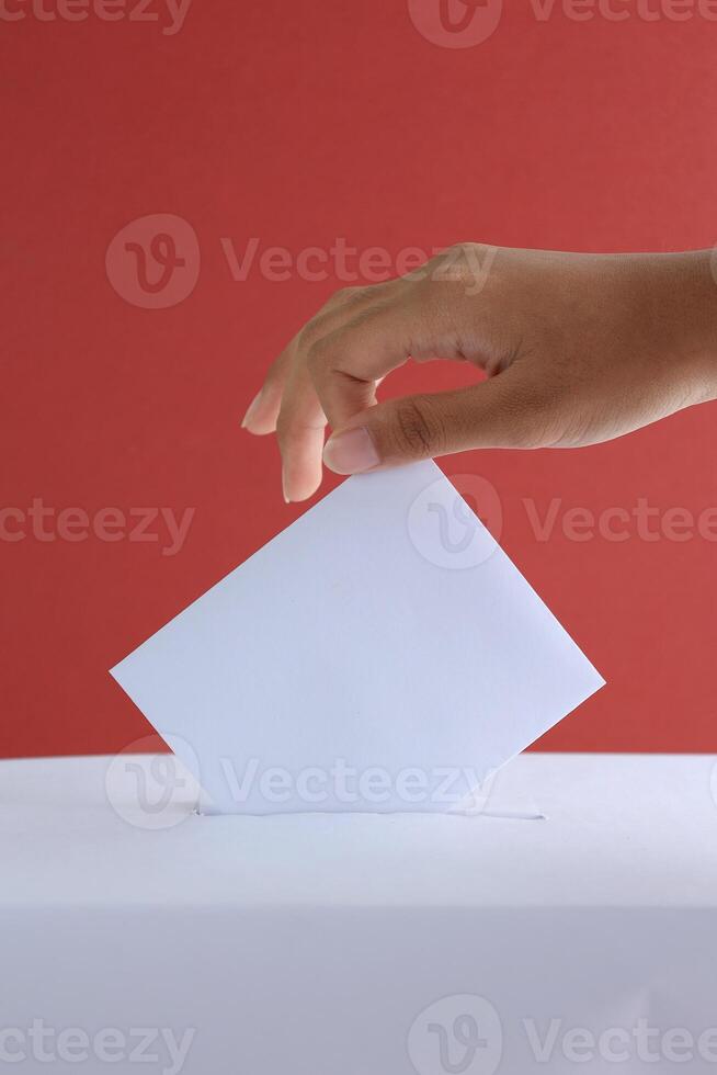 weiblich Hand Wählen in der Nähe von Abstimmung Box auf rot Hintergrund foto