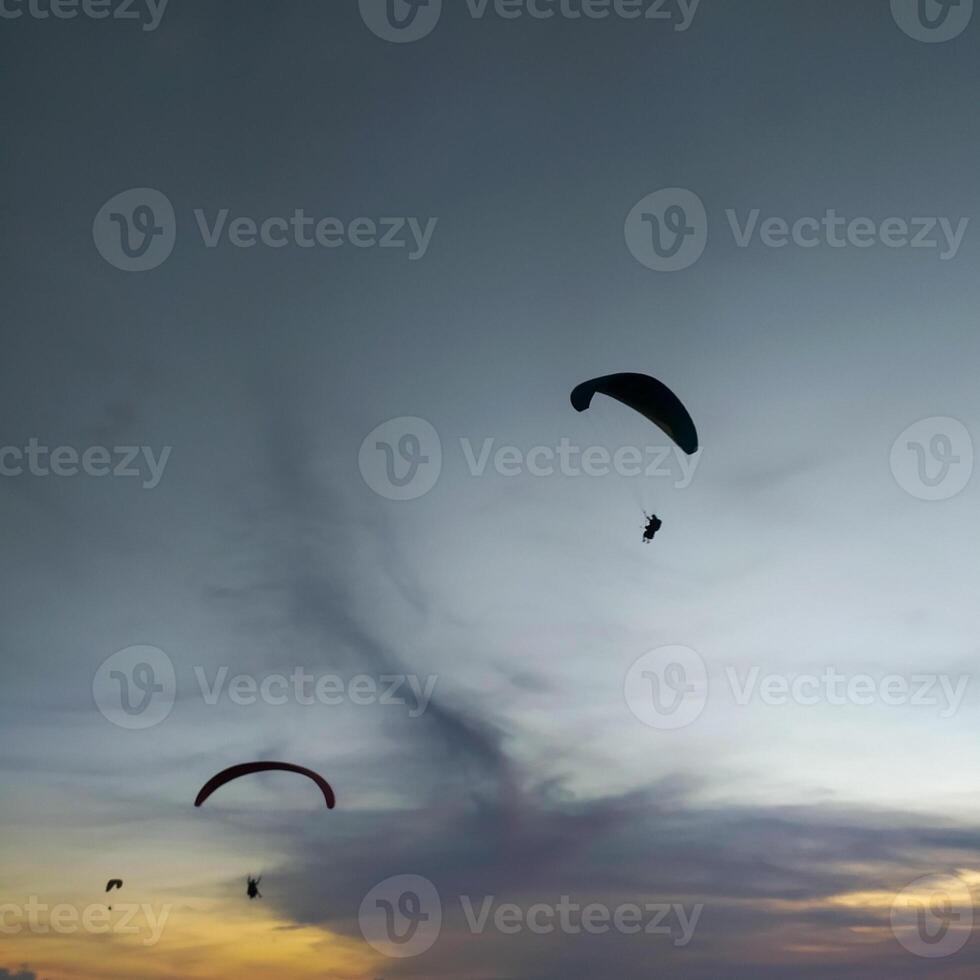 Silhouette von ein Gleitschirm hochfliegend im das Nachmittag Himmel. extrem Sport. foto
