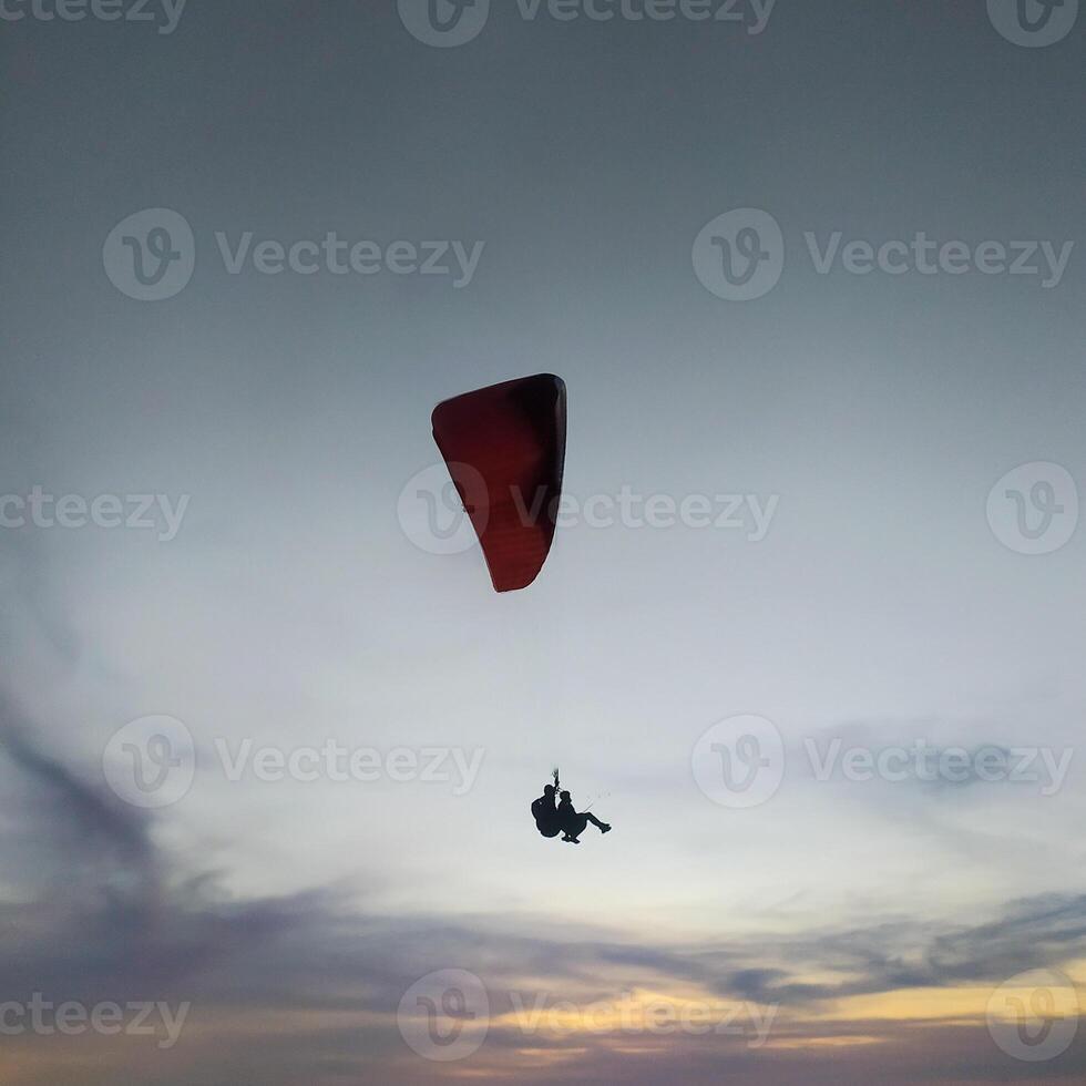 Silhouette von ein Gleitschirm hochfliegend im das Nachmittag Himmel. extrem Sport. foto