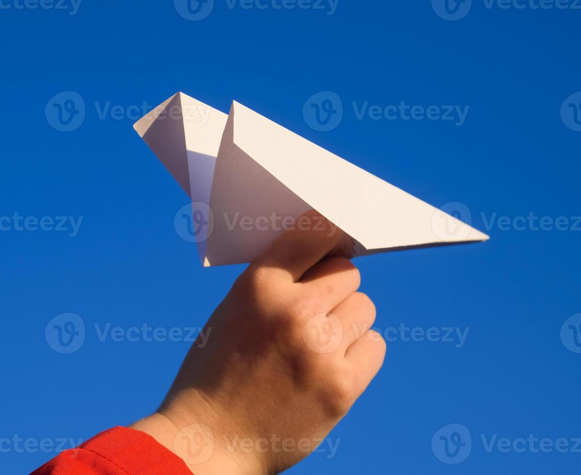 Weiß Papier Flugzeug im Hand gegen das Himmel. ein Symbol von Freiheit auf das Internet foto