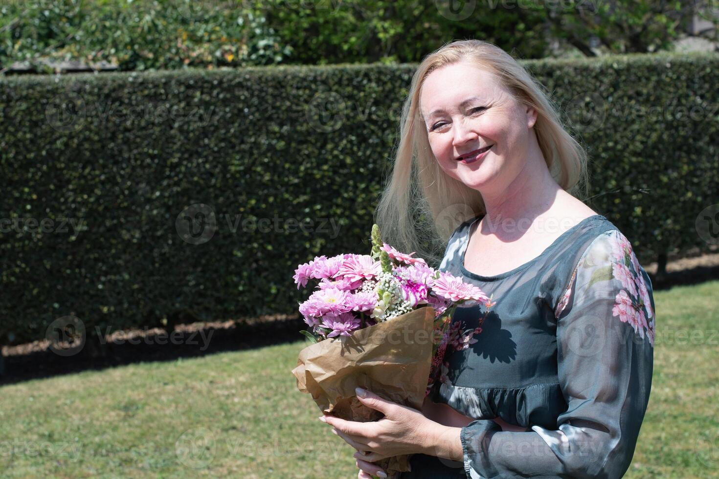 mittleren Alters Frau mit ein Strauß von Rosa Gerbera ein Geschenk zum Mutter Tag, Frühling foto