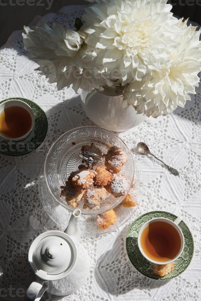 Englisch Stil Tee brechen, immer noch Leben mit Blumen und Donuts im das Morgen Sonne foto