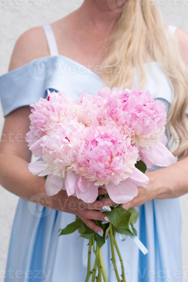 Braut im ein Blau Hochzeit Kleid mit ein Strauß von Rosa Pfingstrosen, Pastell- Paradies foto