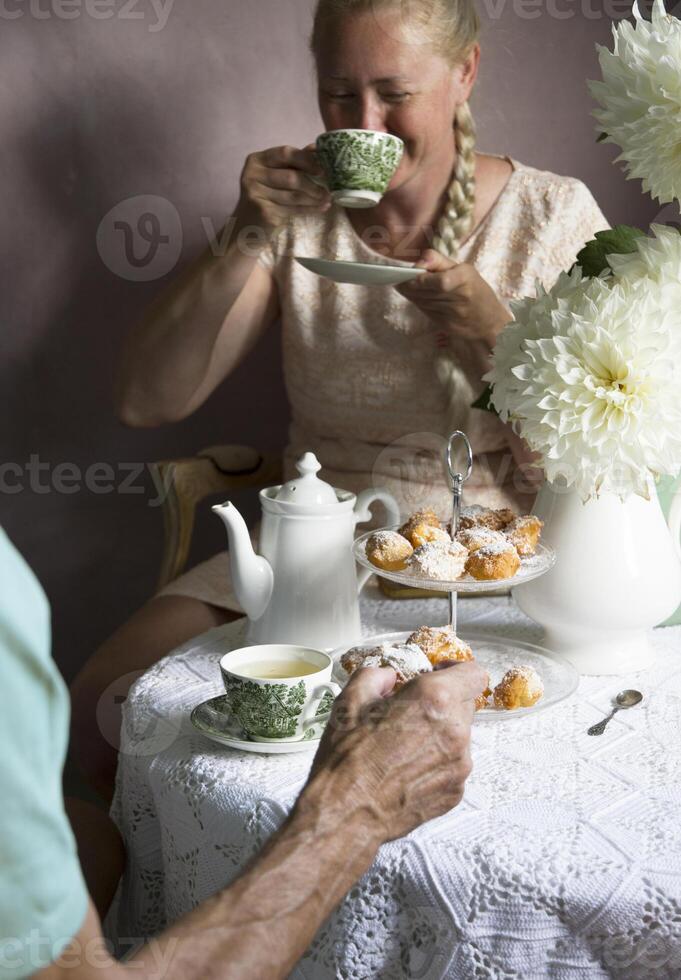 Tee brechen im das Englisch Stil, immer noch Leben mit Blumen und Donuts im das Morgen foto