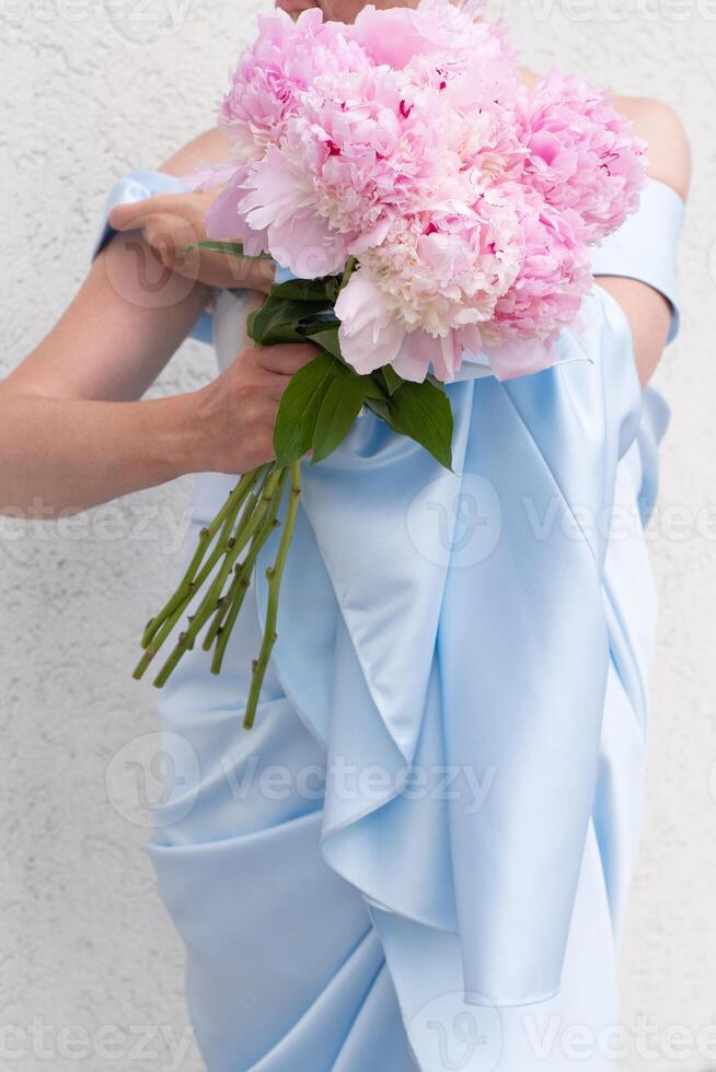 Braut im ein Blau Hochzeit Kleid mit ein Strauß von Rosa Pfingstrosen, Pastell- Paradies foto