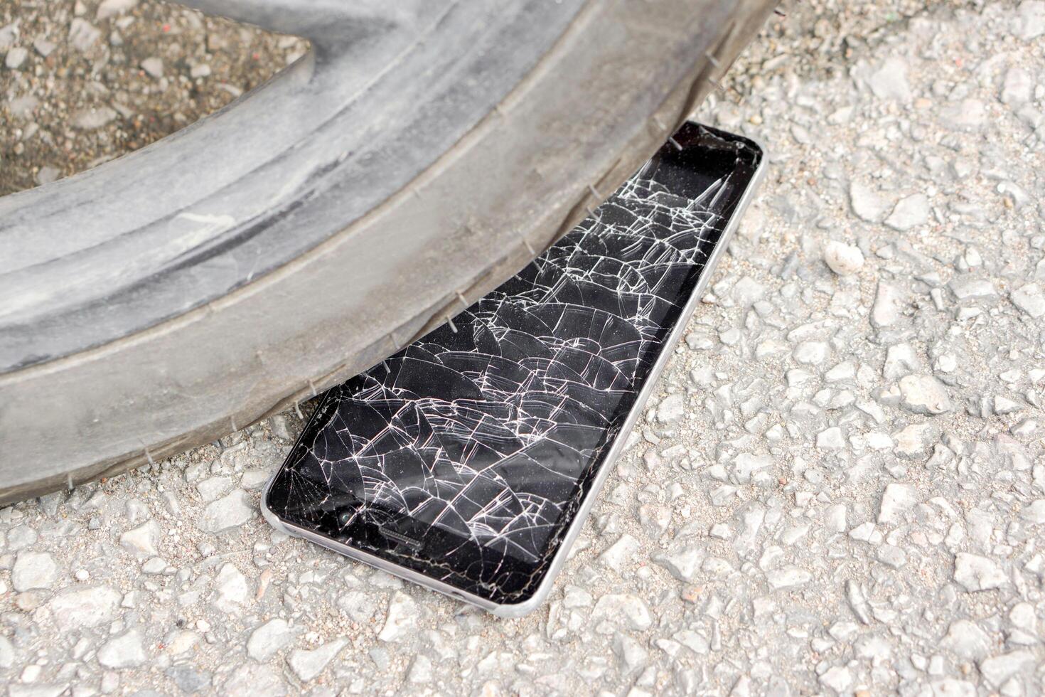 Nahansicht schwarz Handy, Mobiltelefon Telefon Unfall fallen zu das Straße und schlagen durch Motorrad mit Glas gebrochen auf Straße Hintergrund. foto