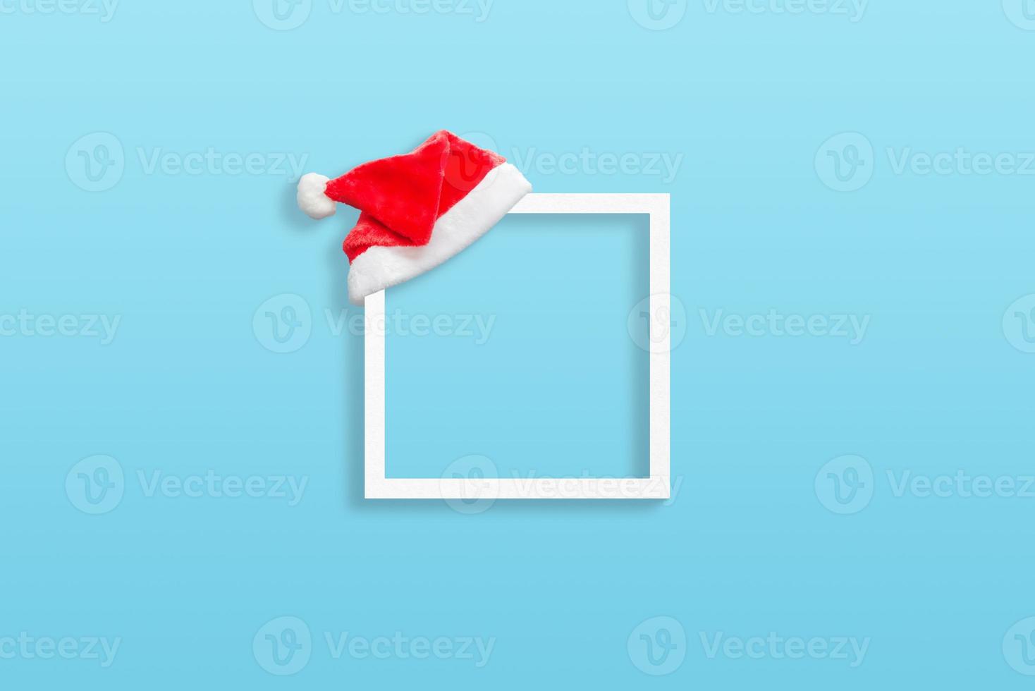 Weihnachten weißer Rahmen mit Weihnachtsmann-Hut auf blauer Pastelloberfläche foto
