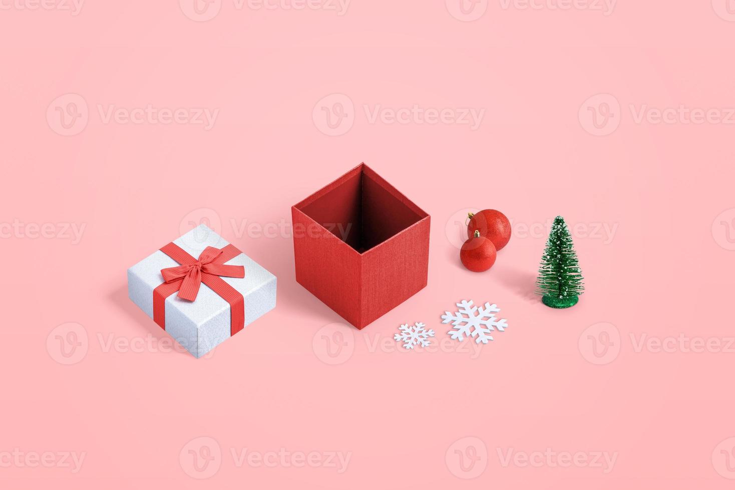 süße geöffnete Weihnachtsgeschenkbox mit mehreren Dekorationen auf pastellrosa Hintergrund foto