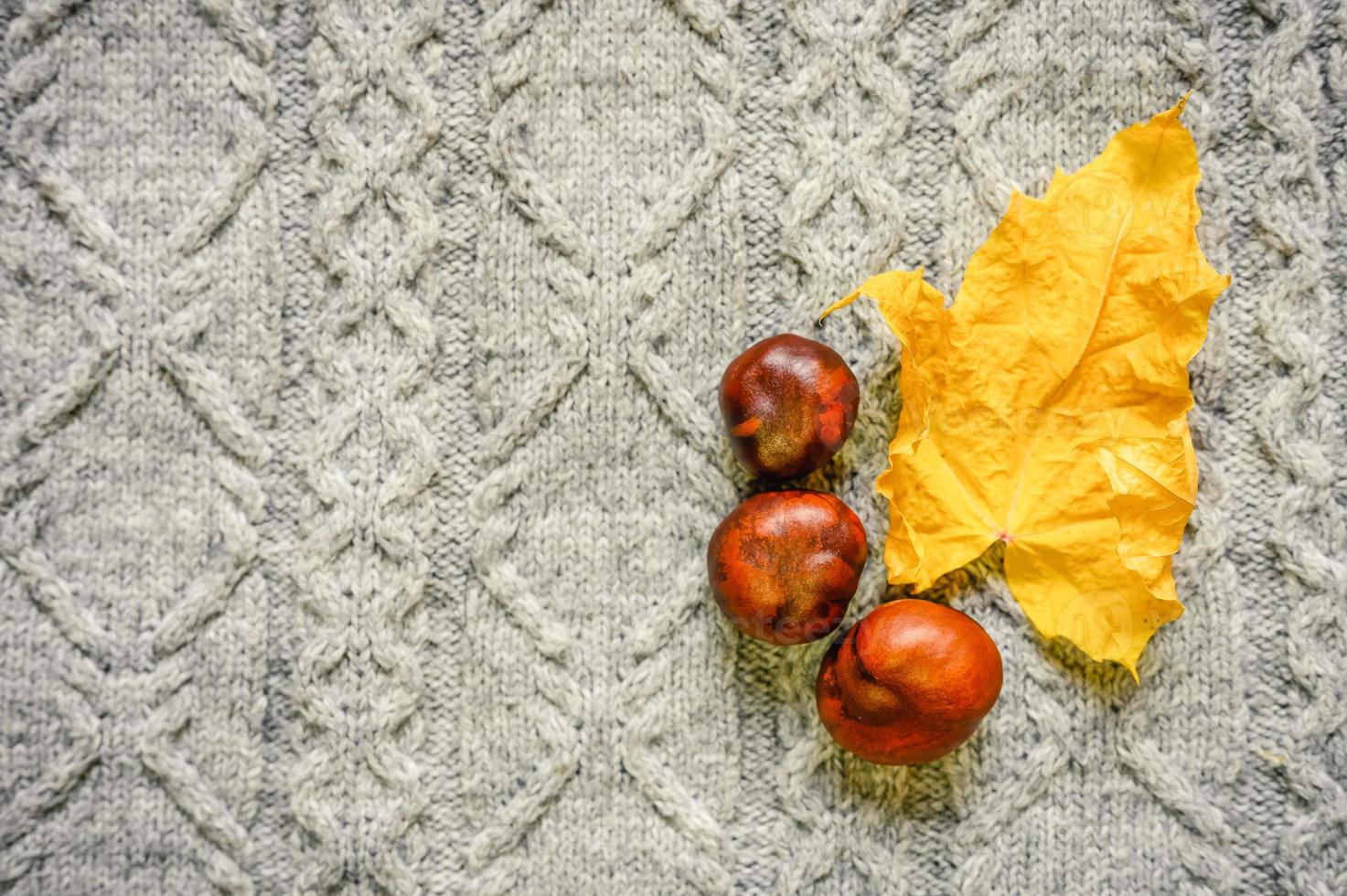 Herbstgelbe und rote Ahornblätter auf dem Hintergrund eines grauen gemütlichen Strickpullovers foto