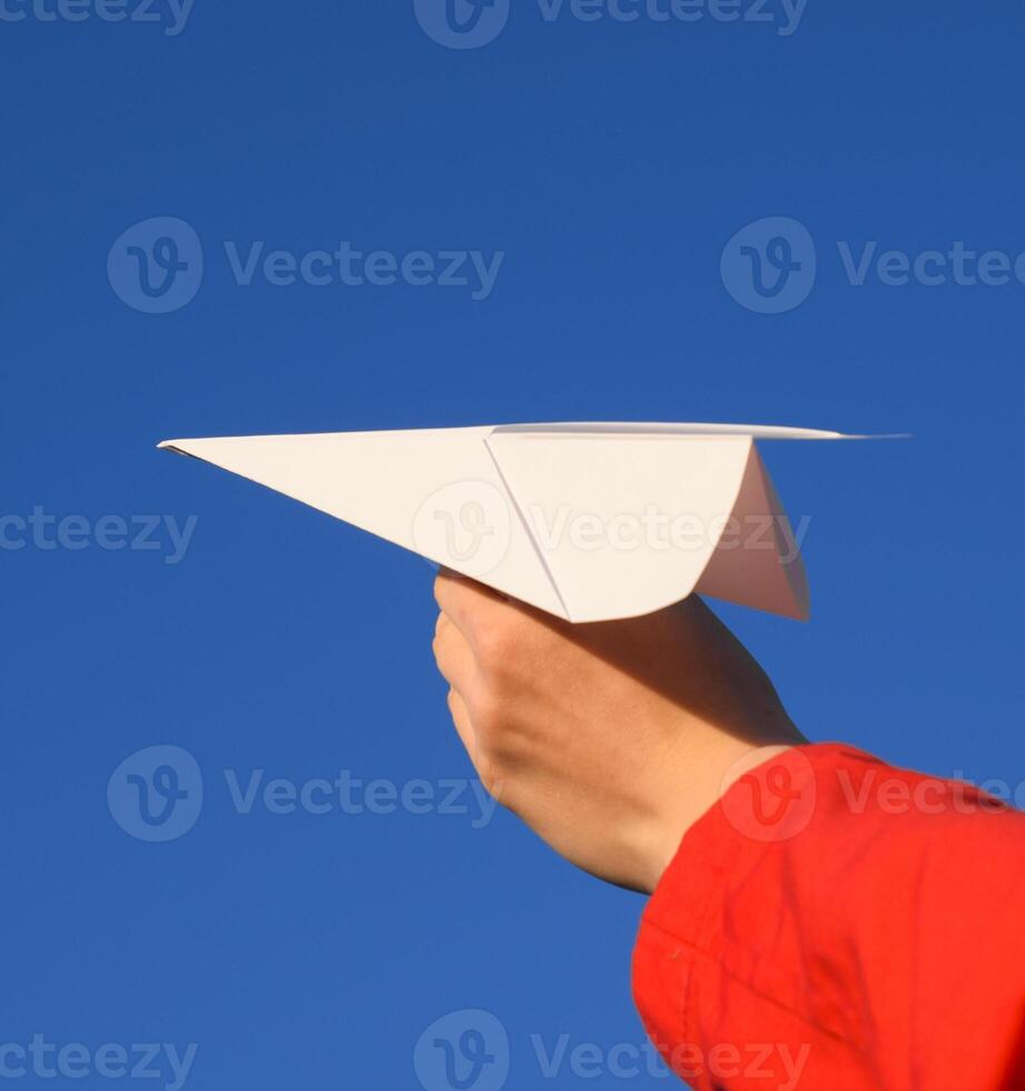 Weiß Papier Flugzeug im Hand gegen das Himmel. ein Symbol von Freiheit auf das Internet foto