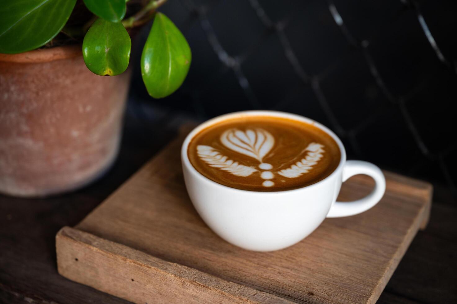 Latté Kunst Kaffee Tasse auf hölzern Teller im dunkel Hintergrund. foto