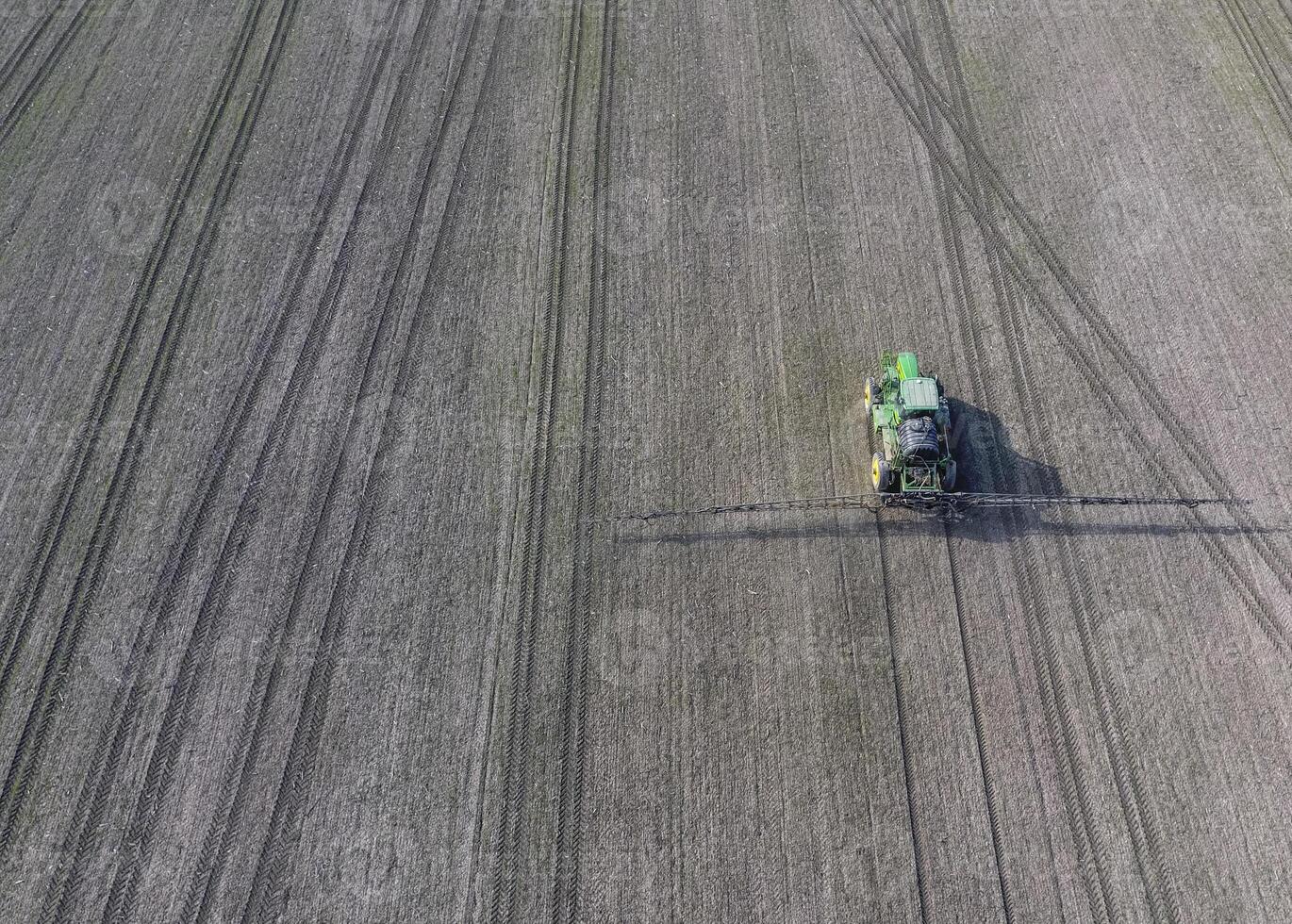 Traktor mit aufklappbar System von Sprühen Pestizide. düngen mit ein Traktor, im das bilden von ein Aerosol, auf das Feld von Winter Weizen. foto
