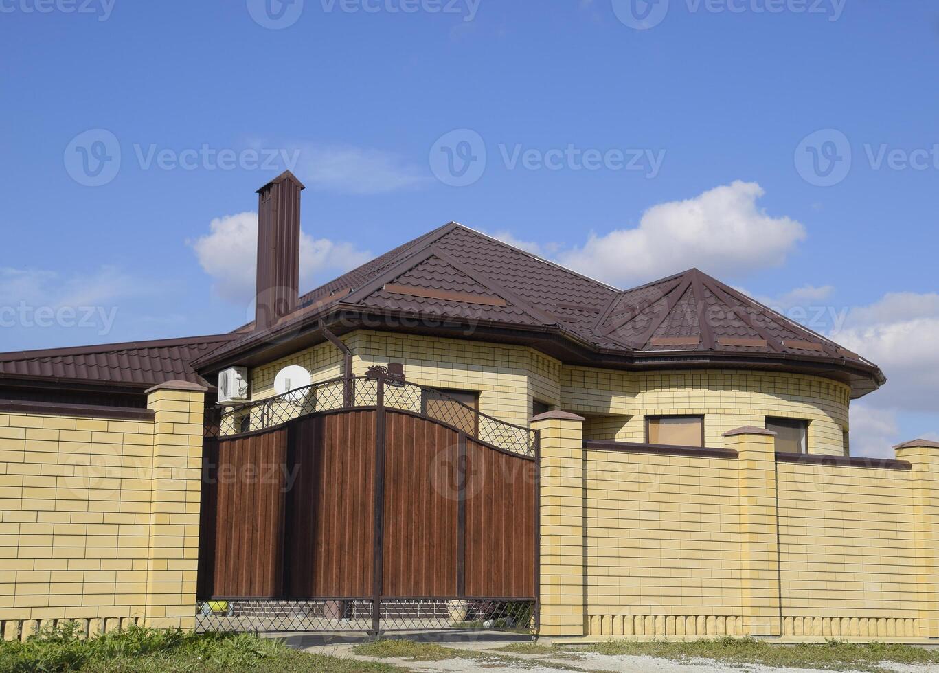 dekorativ Metall auf das Dach von ein Backstein Haus. Zaun gemacht von gewellt Metall. foto